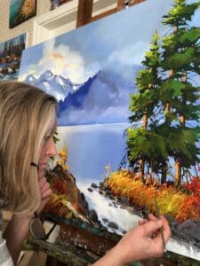 An artist completing a painting of a mountain lake 